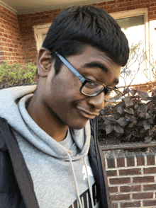 a young man wearing glasses and a grey puma hoodie