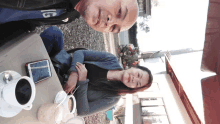 a man wearing a jacket that says lg sits next to a woman sitting at a table