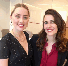 two women standing next to each other smiling for a picture