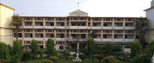 a large building with a lot of windows is surrounded by trees and a statue in front of it .