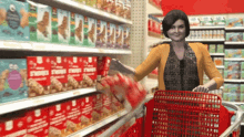 a woman pushing a shopping cart in a grocery store with boxes of strawberries and cream on the shelves behind her