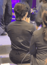 a woman in a black shirt is sitting on a stool