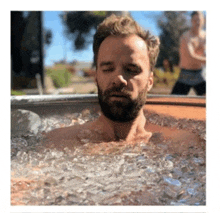 a man with a beard is in a tub of ice