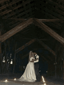 a bride and groom kissing under a wooden structure