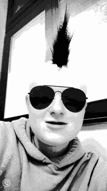 a black and white photo of a man wearing sunglasses and a mohawk on his head