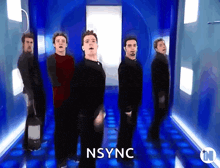 a group of men are dancing in a blue hallway and the word nsync is on the bottom right