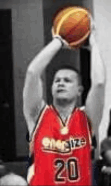 a man in a red energize jersey is holding a basketball above his head