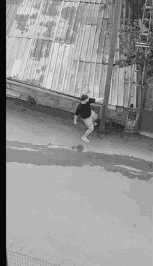 a black and white photo of a man standing on the side of a road .