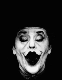 a black and white photo of a clown with a huge smile on his face .