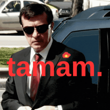 a man in a suit and tie is standing in front of a car with taman written on the bottom