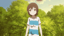 a girl in a blue and white striped shirt stands in front of a forest