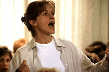 a woman in a white shirt is yelling with her mouth open