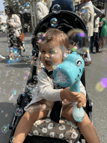 a baby in a stroller playing with bubbles