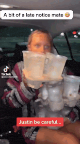 a woman in a car is holding a stack of plastic cups with a tiktok watermark