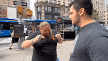 a man with a beard is talking to another man in front of a bus that says lost new york