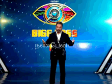 a man in a suit stands in front of a bigg boss sign