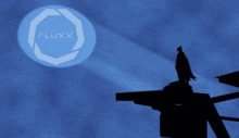 a fluxx logo is projected on a blue background with a batman silhouette in the foreground