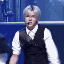 a man wearing a white shirt and a black vest is standing on a stage .