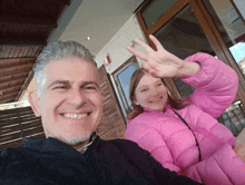 a man and a girl are posing for a picture and the little girl is wearing a pink jacket