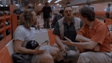 three men are sitting on a bench in a bowling alley with a sign that says 20 on it .