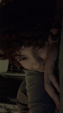 a woman with curly hair is laying down with her hand on her chin