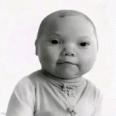 a black and white photo of a baby making a face .