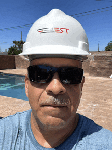 a man wearing sunglasses and a hard hat with the letters est on it