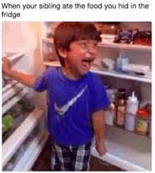 a boy is standing in front of an open refrigerator .