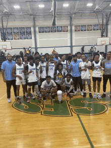 a group of young men are posing for a picture in a gym with a trophy