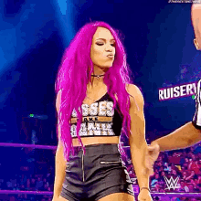 a woman with purple hair is blowing a kiss while wearing a crop top and shorts .