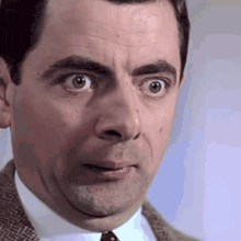 a man wearing a suit and tie is making a surprised face
