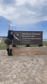 a woman stands in front of a sign that says san juan national historic site castillo san felipe del morro