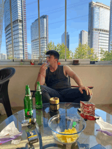 a man sits at a table with a bottle of carlsberg beer and a bowl of chips