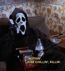 a person in a scream mask is sitting on a couch talking on a cell phone