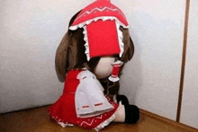 a stuffed doll in a red and white dress is sitting in a corner of a room .