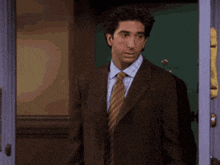 a man in a suit and tie is standing in a doorway with his arms outstretched .