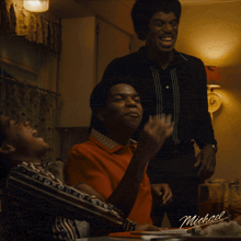 a group of men are sitting at a table with a sign that says michael on it