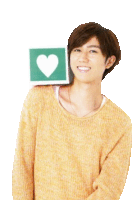 a young man in a yellow sweater is holding a green square with a heart on it over his shoulder