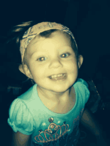 a little girl wearing a headband and a princess shirt smiles for the camera