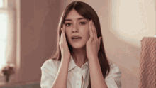 a woman with long hair is touching her face