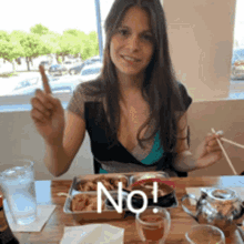 a woman is sitting at a table with a tray of food and the word no written on the table