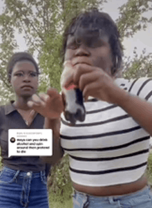 two women are standing next to each other and one is holding a remote control in her hand .