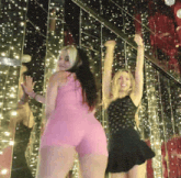 two women are dancing in front of a wall of lights
