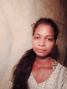 a woman wearing a white shirt with a geometric pattern looks at the camera