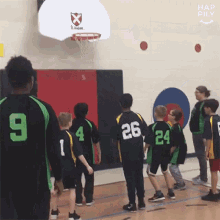 a group of young boys are playing basketball in a gym and one of the boys has the number 26 on his back .