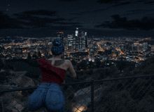 a woman with blue hair and a tattoo on her back looks at a city at night