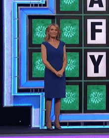 a woman in a blue dress is standing in front of a board with letters a f and y on it