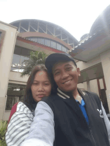 a man and a woman posing for a picture in front of a building