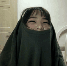 a girl is covering her face with a t-shirt