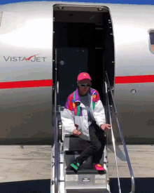 a man sits on the steps of a vista jet